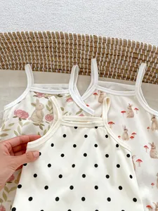 Detail of three cotton baby bodysuits with rabbit prints and polka dots on light fabric