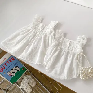 Detail of white cotton baby romper with hollow floral embroidery and lace ruffles