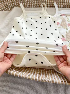 Close-up of elastic ribbed fabric and bottom snaps on cute polka dot baby bodysuit