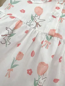 Close-up of cotton baby bodysuit featuring rabbit and pink tulip floral patterns with buttons