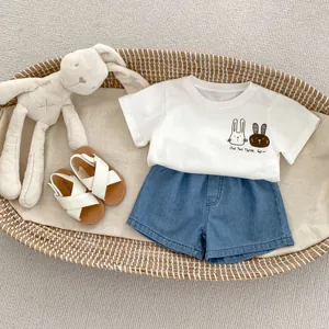Set estivo bimbo con t-shirt con coniglio bianco, shorts in denim e sandali su vassoio