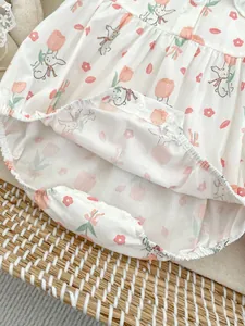 Close-up of baby bodysuit snap fasteners with tulip and rabbit prints on cotton fabric