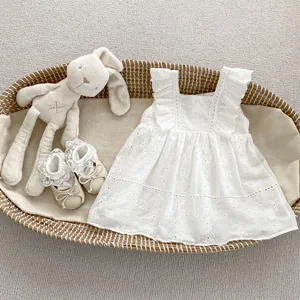 Close-up of white baby bodysuit with floral embroidery and ruffle sleeves in a cradle
