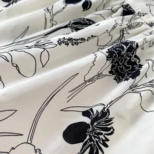 White cotton baby bodysuit with black floral ink painting and soft fabric textures