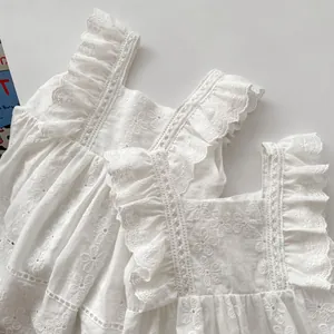Close-up of white cotton baby romper with floral hollow embroidery and ruffle sleeves