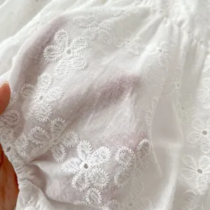 White eyelet embroidery baby romper with delicate lace texture and flutter sleeves