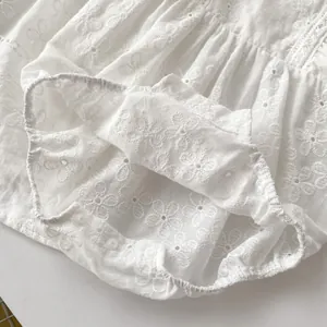 Close-up of white baby bodysuit with floral embroidery and resin snap buttons