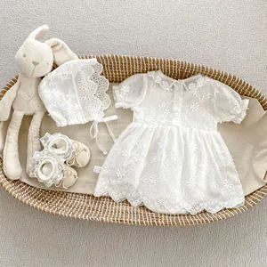 Detailed flat lay of white lace baby romper with matching bonnet and soft walking shoes