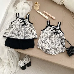 Detail of baby floral cotton romper with vintage print and black bow accents
