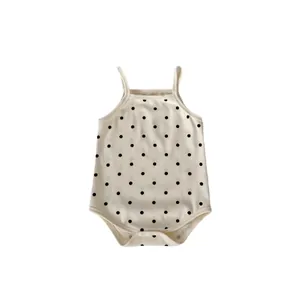 Summer sleeveless baby romper with cute black polka dots on cream cotton fabric