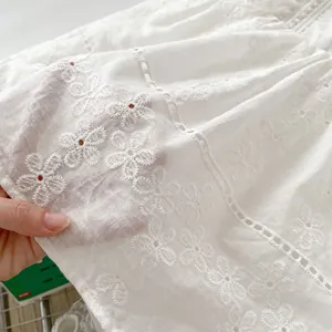 Detailed macro view of white cotton fabric with delicate hollow floral embroidery