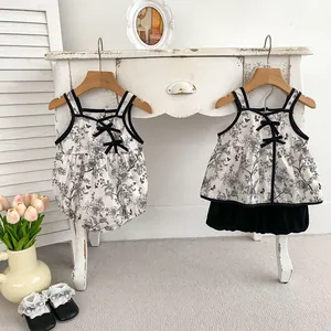 Detailed view of floral baby rompers with black bows and vintage style cotton fabric