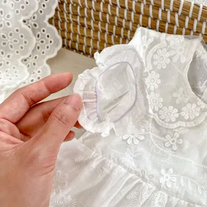 Close-up of white lace baby dress featuring floral embroidery and ruffle elastic cuffs