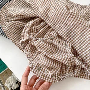 Close-up of baby girl romper with brown gingham pattern and convenient snap buttons