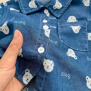 Dettaglio camicia di jeans per bambini con orsetti cartoon e lettere stampate