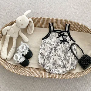 Close-up of baby girl floral romper with black bows and lace shoes in a basket