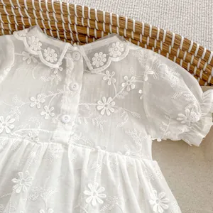 Detailed close-up of baby girl romper dress with floral embroidery and lace collar