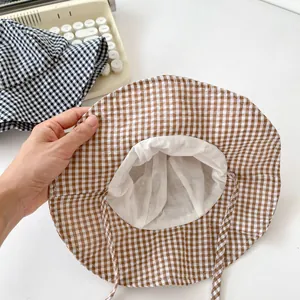 Detailed view of baby sun hat with brown plaid pattern and adjustable chin strap