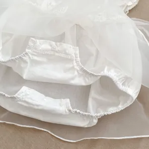 Detalle de body para bebé blanco con cierres a presión y tejido de tul delicado