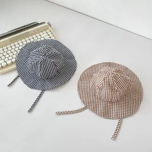 Detail of infant checkered sun hats with chin straps in black and brown plaid patterns