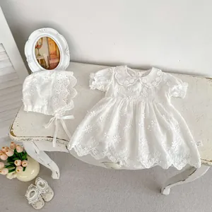 Flat lay of white cotton baby dress set with floral embroidery, matching hat and shoes