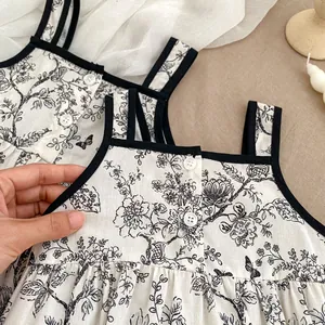 Detail of floral baby bodysuit with black trim, contrast straps, and delicate white buttons