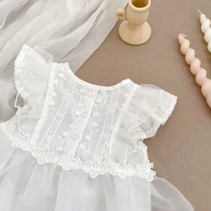 Detalle de mameluco de encaje blanco para bebé con bordado floral y volantes