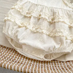 Detailed view of the baby bodysuit with lace embroidery and bottom snap buttons