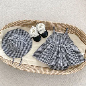 Flat lay of baby girl plaid romper set with sun hat and black shoes in a woven basket