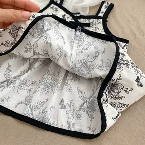 Detail of floral baby bodysuit with black ribbon bow and intricate stitching work
