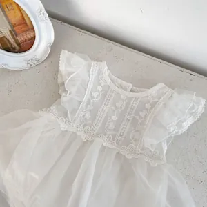Detalle del pelele de encaje blanco para bebé con bordados florales y volantes de tul