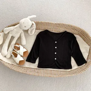 Dettaglio di cardigan bimbo in maglia a coste nere con scollo a V e bottoni bianchi