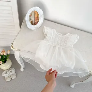 Detalle de pelele blanco para bebé con bordado floral y falda de tul multicapa