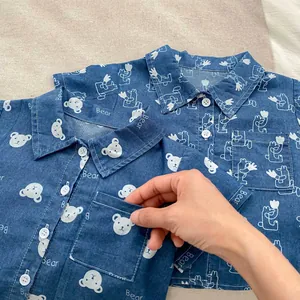 Dettaglio camicia in denim per bambino con orsetti carini e bottoni bianchi