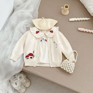 Dettaglio del cardigan in maglia per neonata con ricamo a fungo e colletto a volant