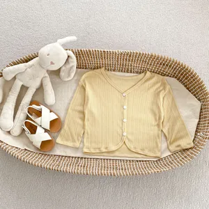 Vista piatta di cardigan per neonati color zenzero con sandali e peluche a coniglio