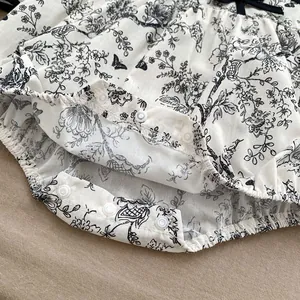 Detail view of cotton floral baby romper featuring snap buttons and elastic leg openings