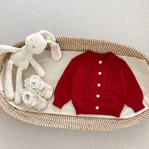 Detail of red hollow knit baby cardigan with diamond patterns and light round buttons