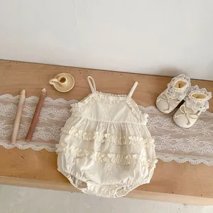Detail view of lace ruffles and floral embroidery on a vintage infant romper with soft shoes