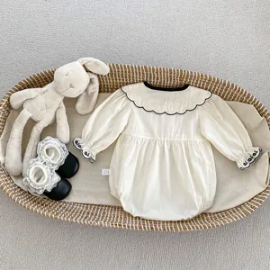Detail van babyrompertje met geschulpte geborduurde kraag en elastische manchetten