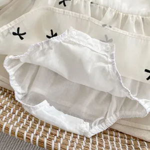 Detail of baby bodysuit featuring black bow patterns and three snap buttons closure