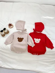 Barboteuses tricotées pour bébé avec patchs d'ours et bonnets assortis sur un lit
