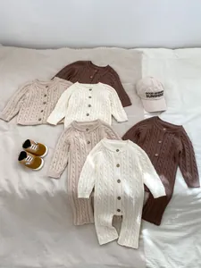 Dettaglio della maglia a trecce e bottoni in legno sulla tutina e cardigan bimbo