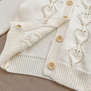 Detailed view of cream hollow knit baby cardigan with wooden buttons and ribbed cuffs