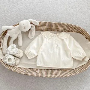 Vista piatta di camicia neonato a maniche lunghe e scarpe in pizzo in un cesto di vimini