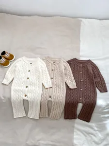 Dettaglio di pagliaccetti in maglia a trecce per neonati in bianco, beige e marrone