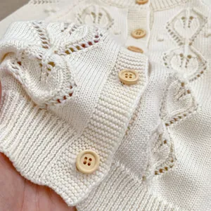 Detail of baby knit cardigan showing hollow out pattern and round wooden buttons