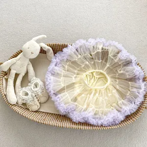 Close-up of a layered yellow mesh tutu skirt with lace baby shoes in a woven basket