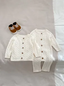Dettaglio della maglia a trecce bianco sporco e bottoni in legno vintage sulla tutina