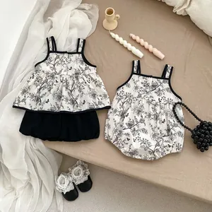 Flat lay of vintage floral baby summer romper and matching two-piece set on a linen cloth
